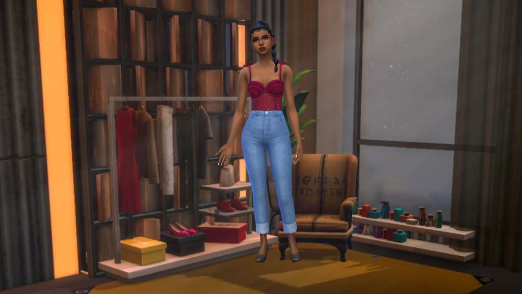 A sim in high waisted blue jeans and a red corset bodysuit with their hair in a braid. This sim is standing in a room with industrial style, a small chair and a clothing rack.